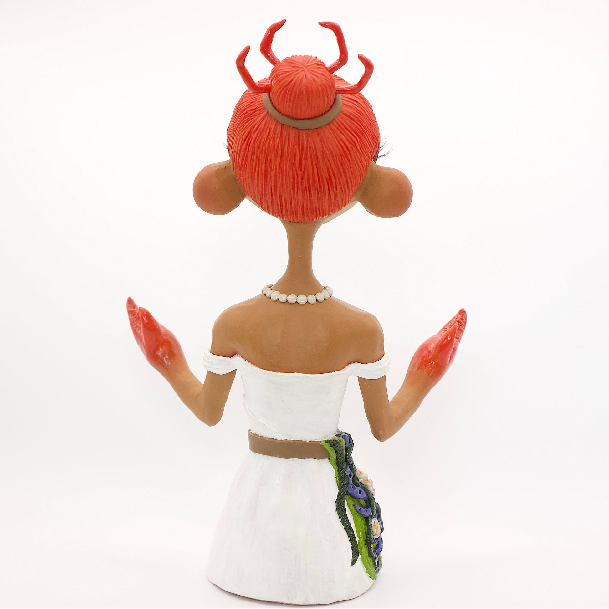 A polymer clay sculpture of the Cancer zodiac personified as a woman, featuring a seaweed belt, crab claws for hands and crab legs in her hair, she is wearing a white dress decorated with sea shells.