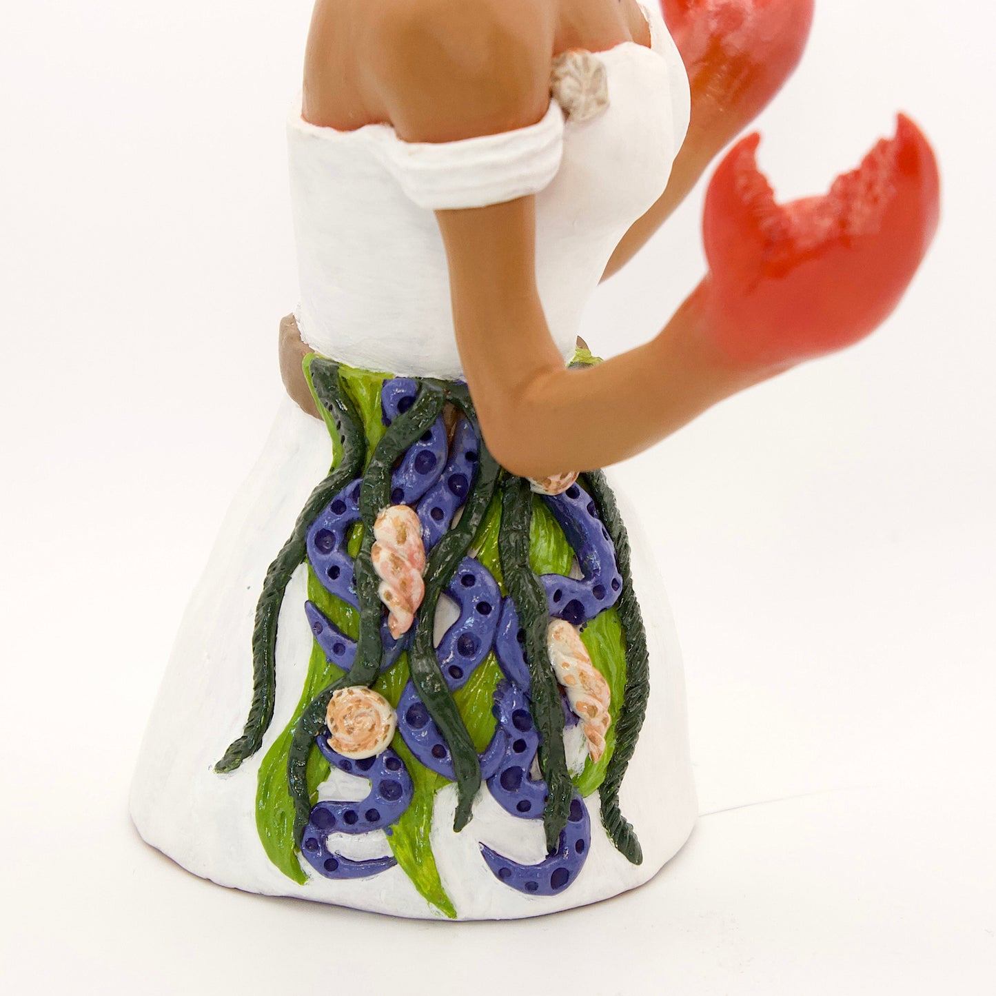 A polymer clay sculpture of the Cancer zodiac personified as a woman, featuring a seaweed belt, crab claws for hands and crab legs in her hair, she is wearing a white dress decorated with sea shells.