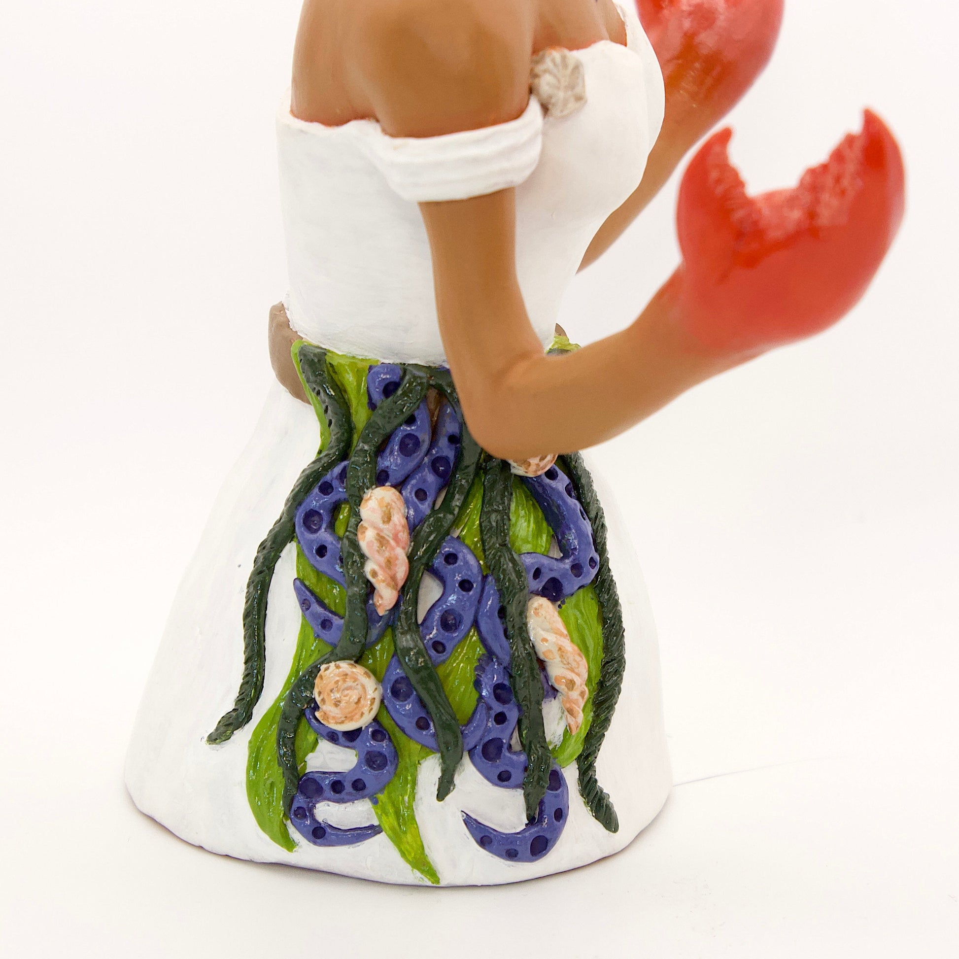 A polymer clay sculpture of the Cancer zodiac personified as a woman, featuring a seaweed belt, crab claws for hands and crab legs in her hair, she is wearing a white dress decorated with sea shells.