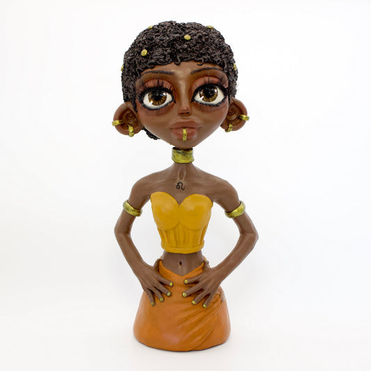 A polymer clay sculpture of the Leo zodiac personified as a woman, featuring yellow, orange and gold tones, and a mane-like afro hairstyle.